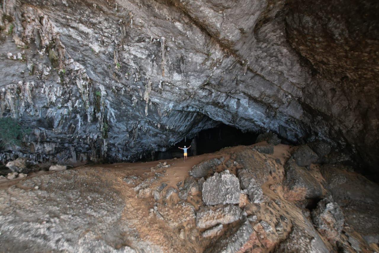 Explorer standing inside a vast Socotra cave with arms raised